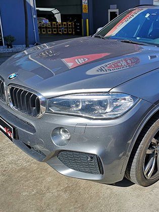 After: a grey BMW with a clean, straight, freshly finished front end.