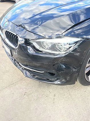 Before: a dark grey BMW with impact damage along the front bumper, wing and headlight.
